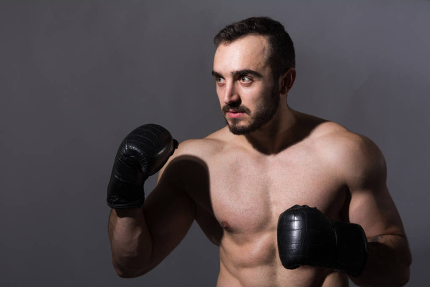 Portrait of a young muscular man in boxing gloves in a pose - Photo, Image