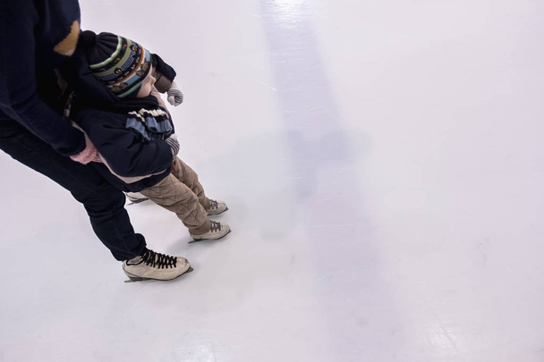 Happy family, mother teaches son ice skating at rink. - Zdjęcie, obraz