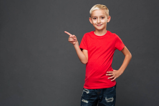 Photo of cheerful little boy child standing isolated over grey background. Looking camera pointing. - Foto, Imagen