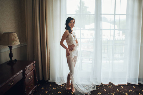 beautiful caucasian bride in lingerie posing at camera in hotel room - Fotografie, Obrázek