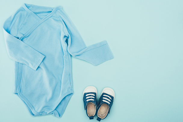 top view of baby bodysuit and shoes isolated on blue - Foto, afbeelding
