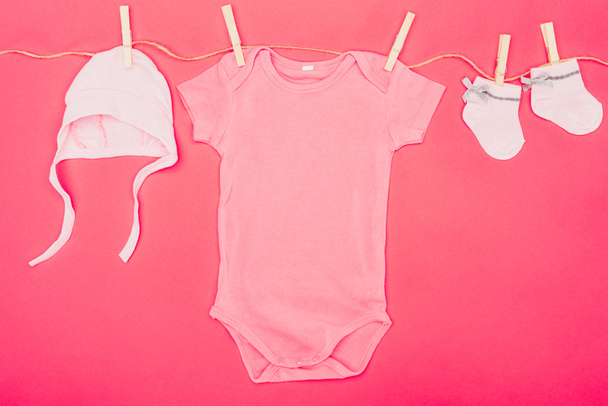 top view of baby clothes drying on rope isolated on red - Photo, Image