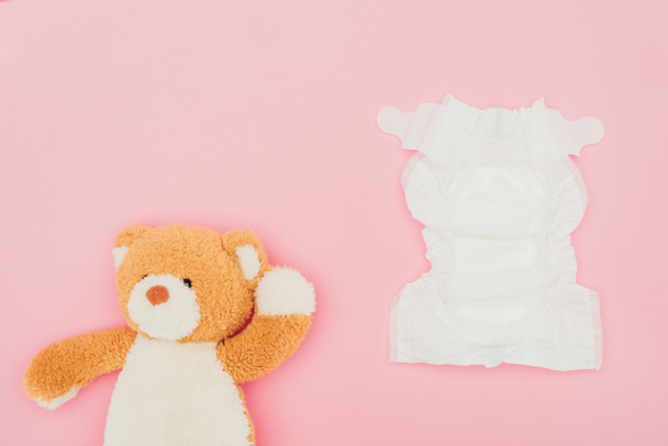 top view of teddy bear and unused diaper isolated on pink - Photo, Image