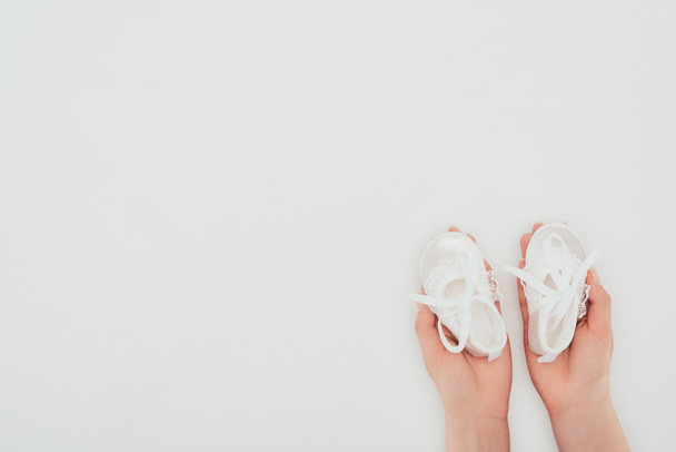 image recadrée de la femme tenant des chaussures de bébé blanches isolées sur blanc
 - Photo, image