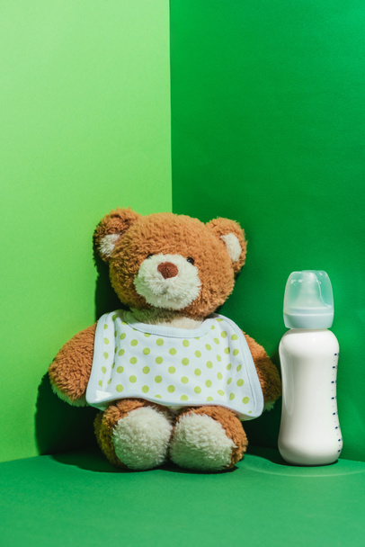 teddy bear and baby bottle with milk on green - Photo, Image