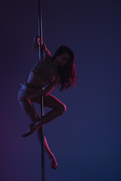 full length view of beautiful sporty girl dancing with pole on blue  - Foto, Bild