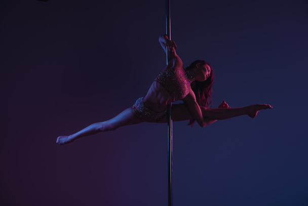full length view of beautiful flexible girl dancing with pole on blue - Foto, afbeelding