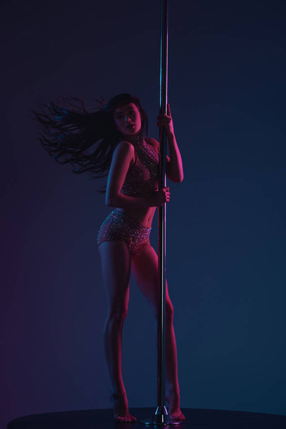 vista completa de la hermosa mujer joven deportiva posando con poste en azul
 - Foto, imagen