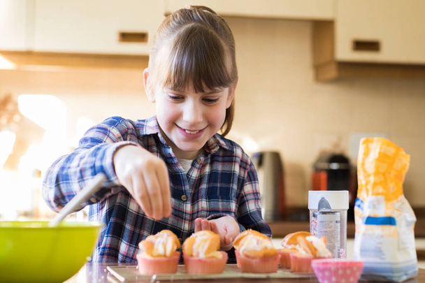 Girl In Kitchen Decorating Home Made Cupcakes - 写真・画像