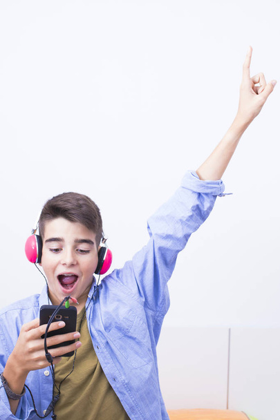 εφηβικό αγόρι με κινητό τηλέφωνο και τα ακουστικά να ακούτε μουσική - Φωτογραφία, εικόνα