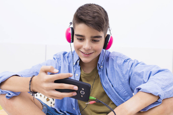 teenage boy with mobile phone and headphones listening to music - Valokuva, kuva