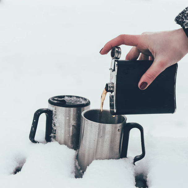 partial view of woman pouring coffee into cups in snow in winter - Φωτογραφία, εικόνα