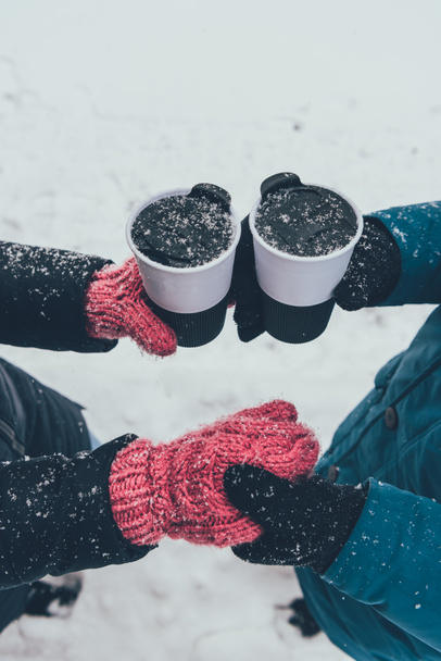 vista parcial de pareja con bebidas calientes cogidas de la mano en la calle en invierno
 - Foto, Imagen