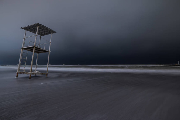 Night photo of the severe winter sea. Long exposure.  Rescue tower on the shore. - Photo, Image