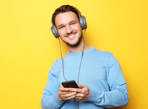 Handsome Man lictening to music over yellow background - Foto, afbeelding