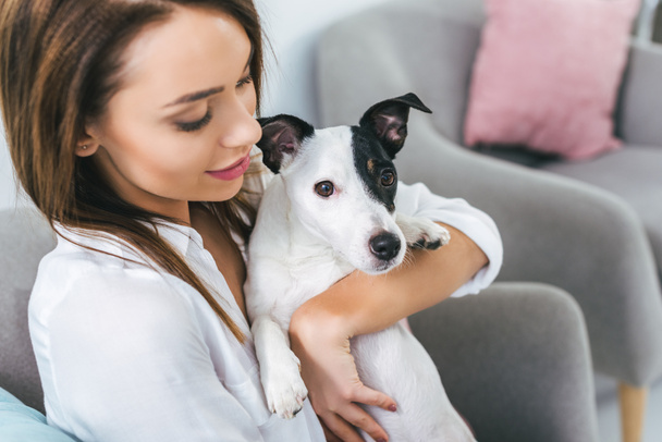beautiful woman with jack russell terrier dog sitting on sofa - Foto, Bild