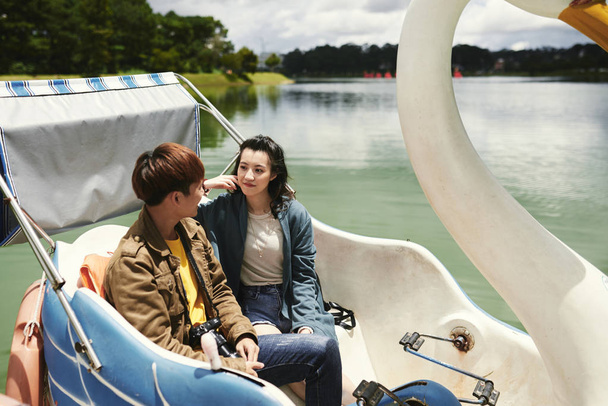 Joven pareja asiática hablando y disfrutando de paseo en barco por el río
 - Foto, Imagen
