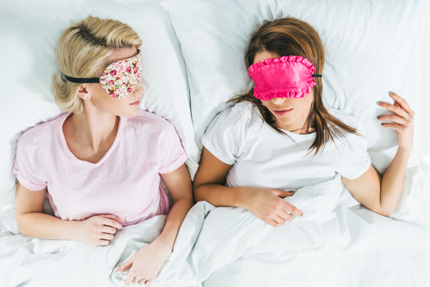 top view of young girls sleeping in masks on bed - Foto, imagen