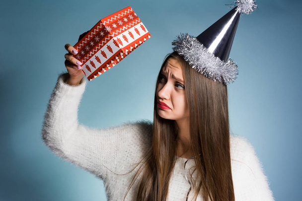 sad woman in festive cap holding empty gift box - Fotoğraf, Görsel