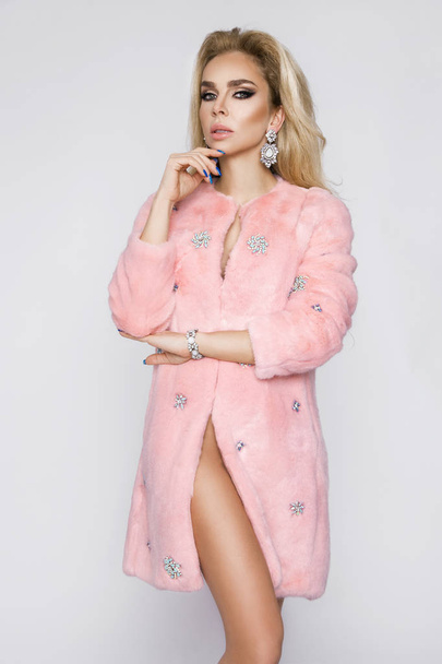 Beautiful, sexy naked blond model, dressed only in elegant pink fur. - Foto, afbeelding
