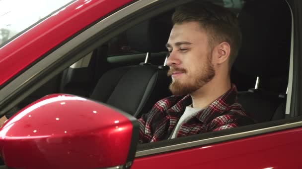 Красивий молодий чоловік зручно сидить у своїй новій машині, посміхаючись камері
 - Кадри, відео
