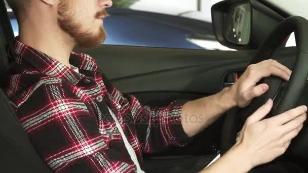 Tiro cortado de um homem barbudo sentado em um carro segurando o volante
 - Filmagem, Vídeo