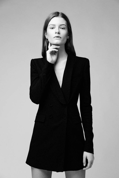 Gorgeous fashion model in black fashionable jacket posing against studio background - Photo, Image