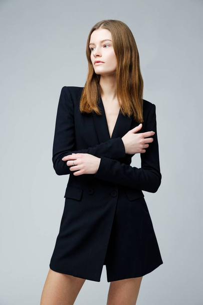 Gorgeous fashion model in black fashionable jacket posing against studio background - 写真・画像