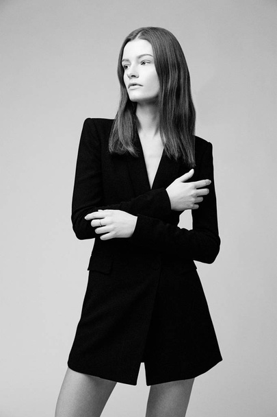 Gorgeous fashion model in black fashionable jacket posing against studio background - Foto, Imagem