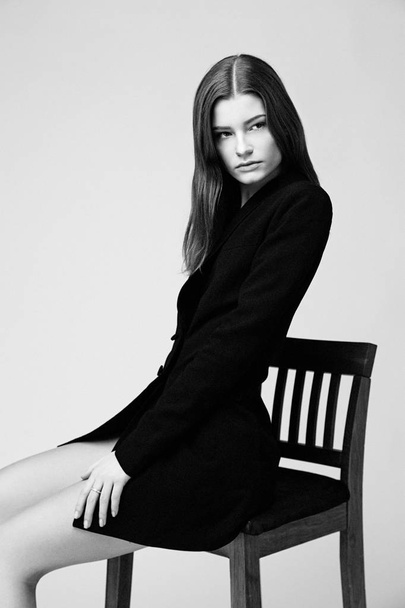 Attractive fashion model sitting on bar stool against studio background  - Фото, зображення