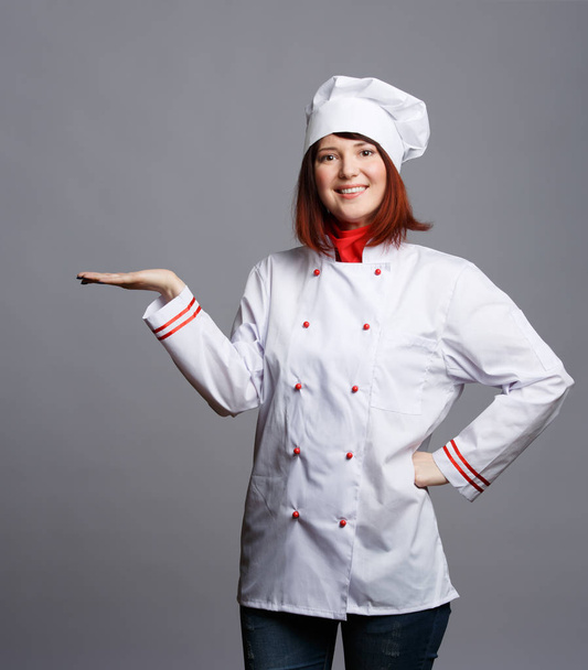 Photo of smiling brunette chef in white robe with empty palm - Photo, Image