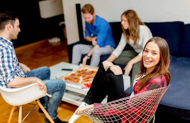 家でピザを食べる若い友人のグループ - 写真・画像