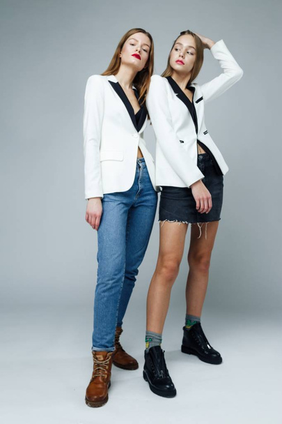 Two stylish fashion models posing against studio background - Fotoğraf, Görsel