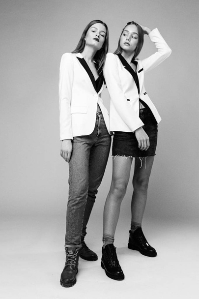 Two stylish fashion models posing against studio background - 写真・画像