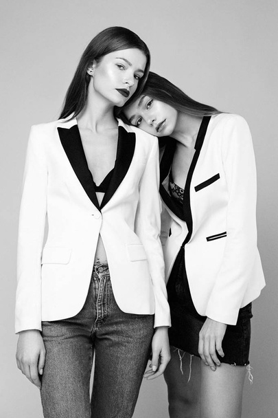 Two stylish fashion models posing against studio background - Фото, зображення