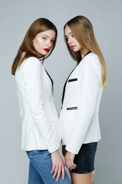 Two stylish fashion models posing against studio background - Фото, зображення