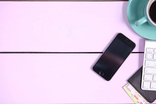 Moderne werkruimte met koffiekopje, toetsenbord en smartphone kopiëren ruimte op roze kleur achtergrond. Bovenaanzicht. Plat lag stijl - Foto, afbeelding
