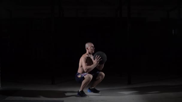 The athlete does sit-ups with the ball on his chest in the gym. - Záběry, video