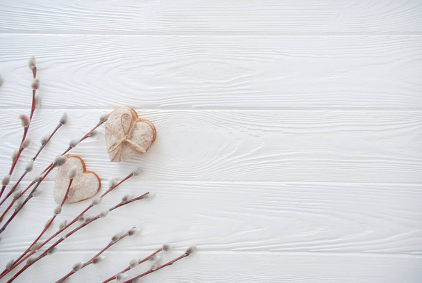 Fond printanier. Chatte branches de saule et biscuits de pain d'épice en forme de coeur sur panneau de bois blanc. Pose plate, vue du dessus avec espace de copie
. - Photo, image