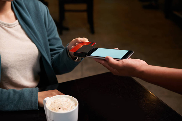 Nainen asiakas pyyhkäisemällä kortti maksaa kahvia
 - Valokuva, kuva