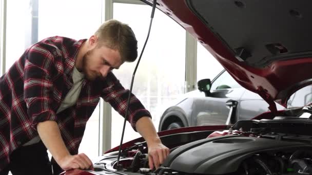 Bonito cutomer masculino examinando motor de um carro no showroom concessionária
 - Filmagem, Vídeo