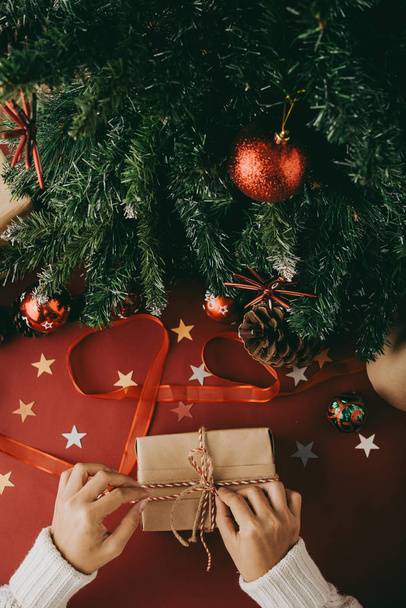 Manos de la persona atando arco en regalo de Navidad, vista desde arriba
 - Foto, Imagen