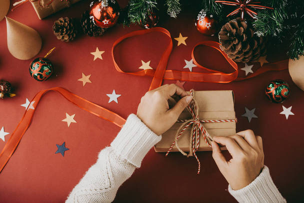 Woman tying bow on Christmas present to decorate it - Φωτογραφία, εικόνα
