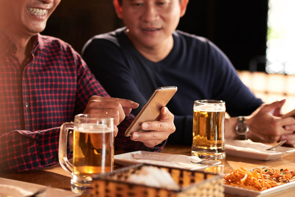 Close-up image of men using application on smartphone when meeting with friends - Photo, image