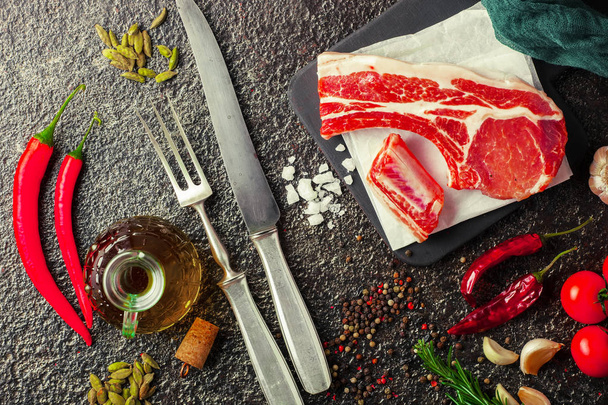 Raw meat on the kitchen table on a metallic background in a composition with cooking accessories - Foto, Imagen