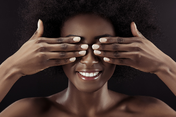 hermosa mujer afroamericana que cubre los ojos con las manos aisladas en negro
 - Foto, Imagen