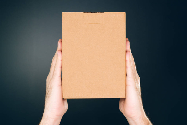 Man holding cardboard box package for mock up design - Foto, afbeelding