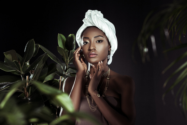 young african american woman in white wire head wrap behind leaves - Zdjęcie, obraz