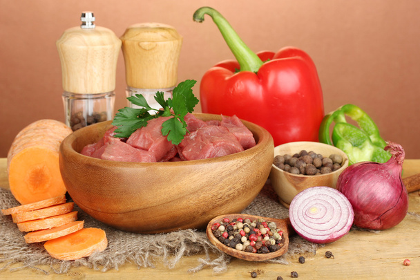 Raw beef meat marinated with herbs and spices on wooden table on brown background - Foto, Bild