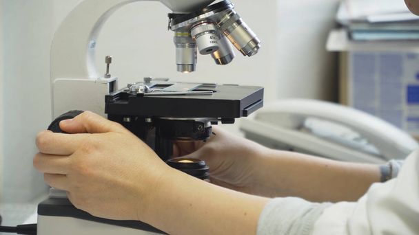 Woman doctor looks in a microscope. - Fotoğraf, Görsel